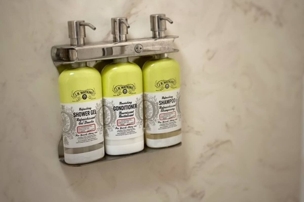 Three bottles of J.R. Watkins personal care products mounted on a wall.