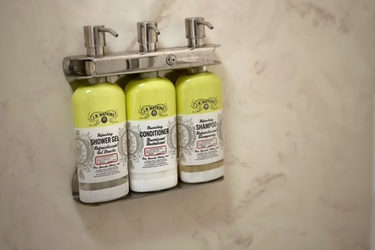 Three bottles of J.R. Watkins personal care products mounted on a wall.