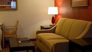 A hotel room with a sofa, a small table, a lamp, and a chair. - Holiday Inn Express Hotel & Suites Oxford by IHG (Oxford)