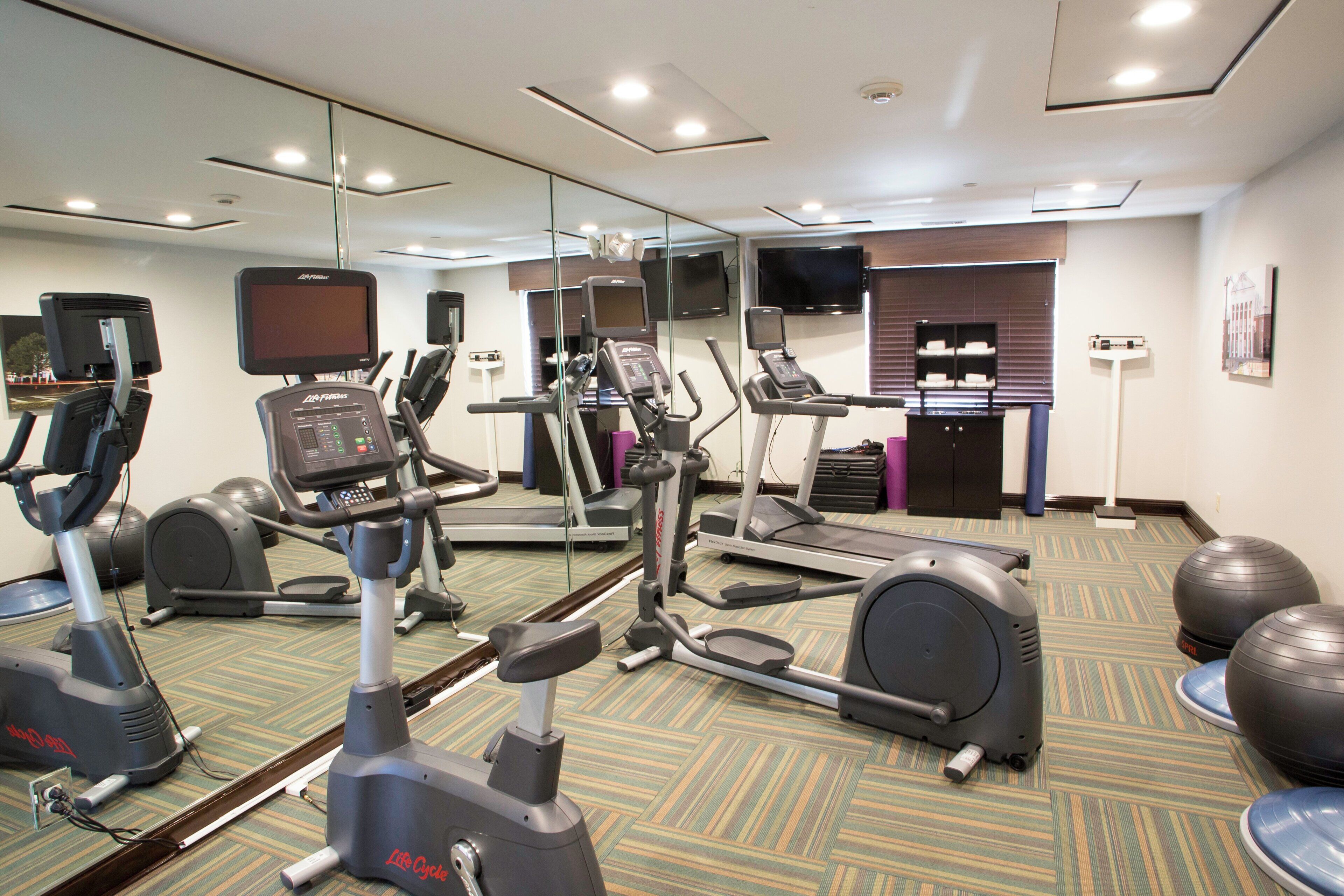 A gym with various exercise equipment including treadmills, stationary bikes, and elliptical machines.
