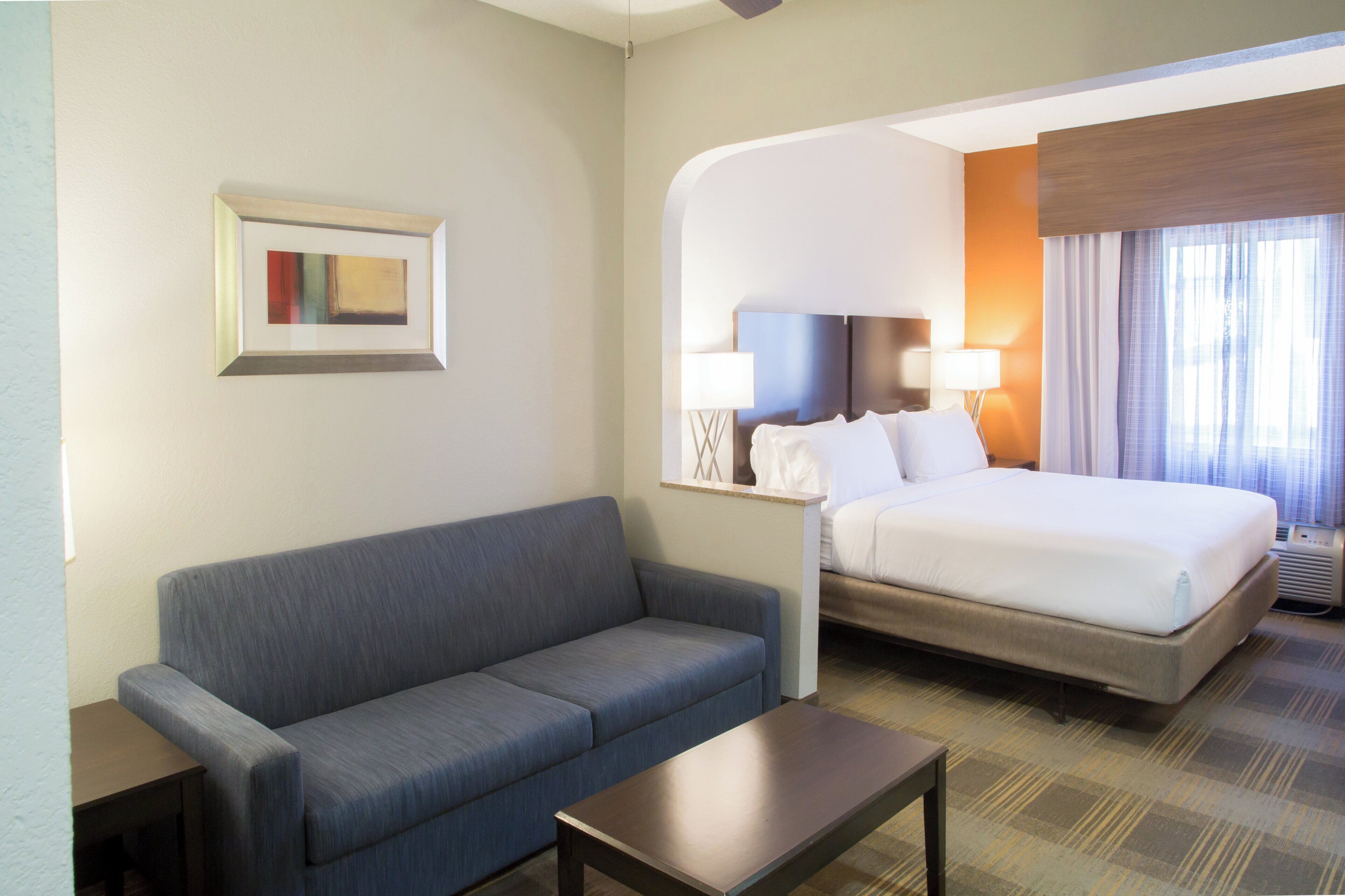 Une chambre d’hôtel avec un lit, un canapé, une petite table et un tableau au mur.