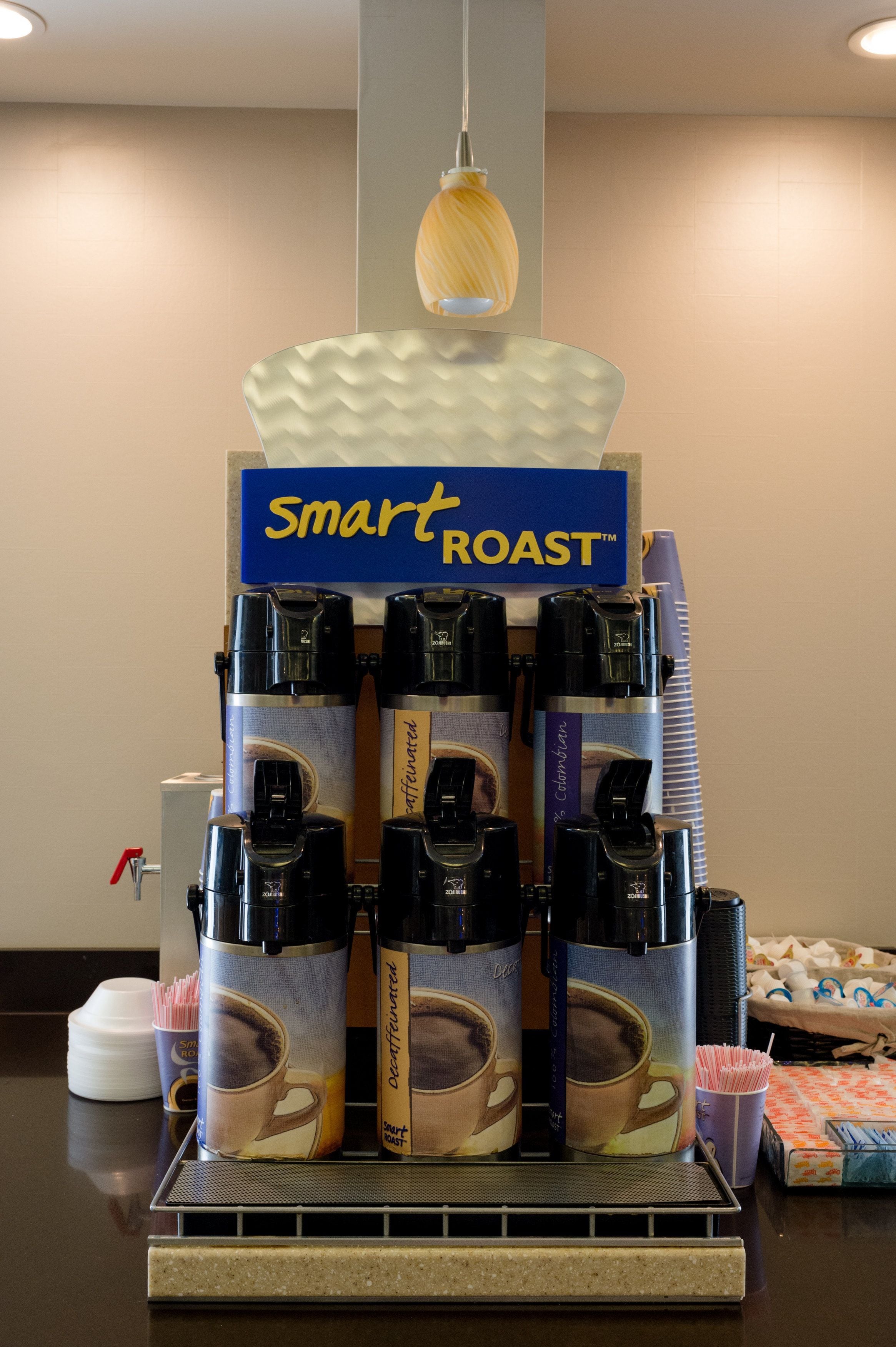 A coffee station with multiple coffee dispensers and a sign that reads "Smart Roast."