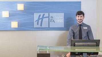 Una recepción de hotel con un separador de vidrio, una placa de identificación y un letrero de Holiday Inn Express.