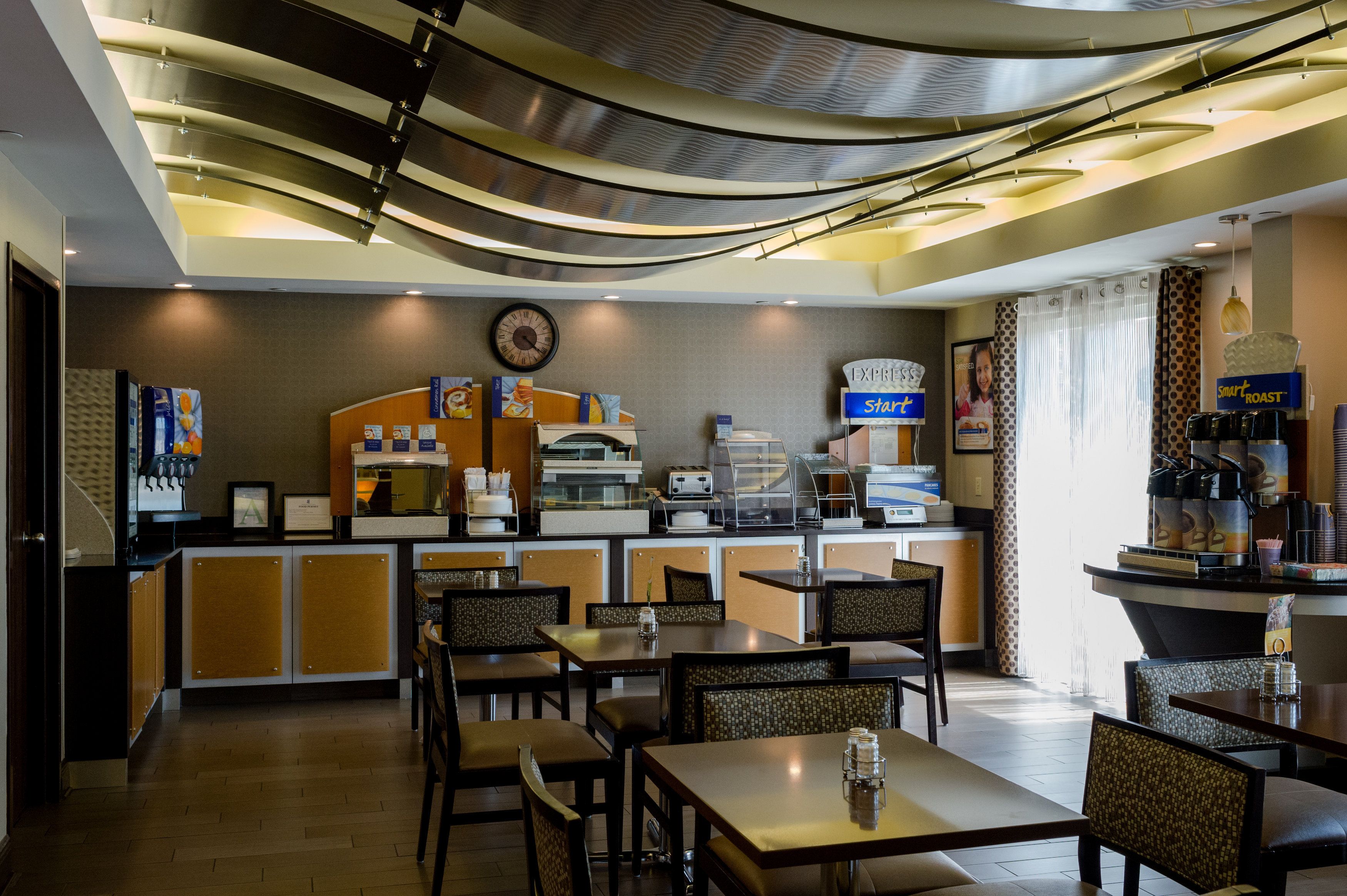 A modern restaurant with a counter, seating area, and a coffee station.