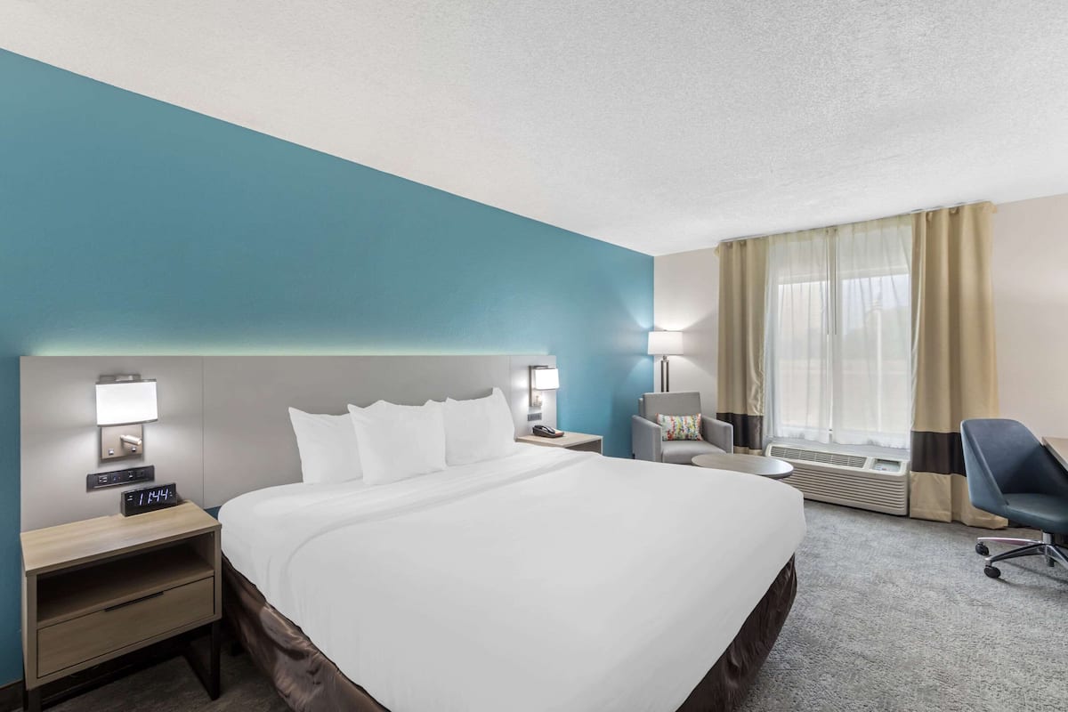 A hotel room with a large bed, bedside tables, a desk, and a chair.
