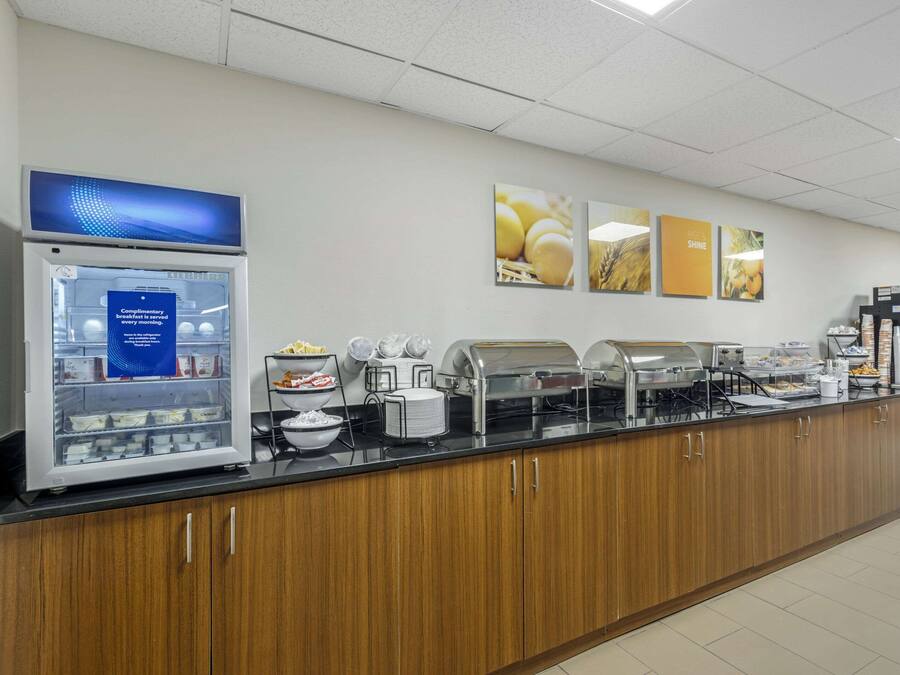A buffet setup with a refrigerator, various food stations, and a wall with informational posters.