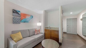 A modern living room with a grey sofa, a small round table, and a cabinet. There are three wall art pieces above the sofa. - Comfort Inn US Hwy 80 (Demopolis)