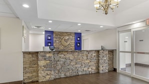 A reception area with a stone wall, a blue accent wall, and a chandelier. - Comfort Inn US Hwy 80 (Demopolis)