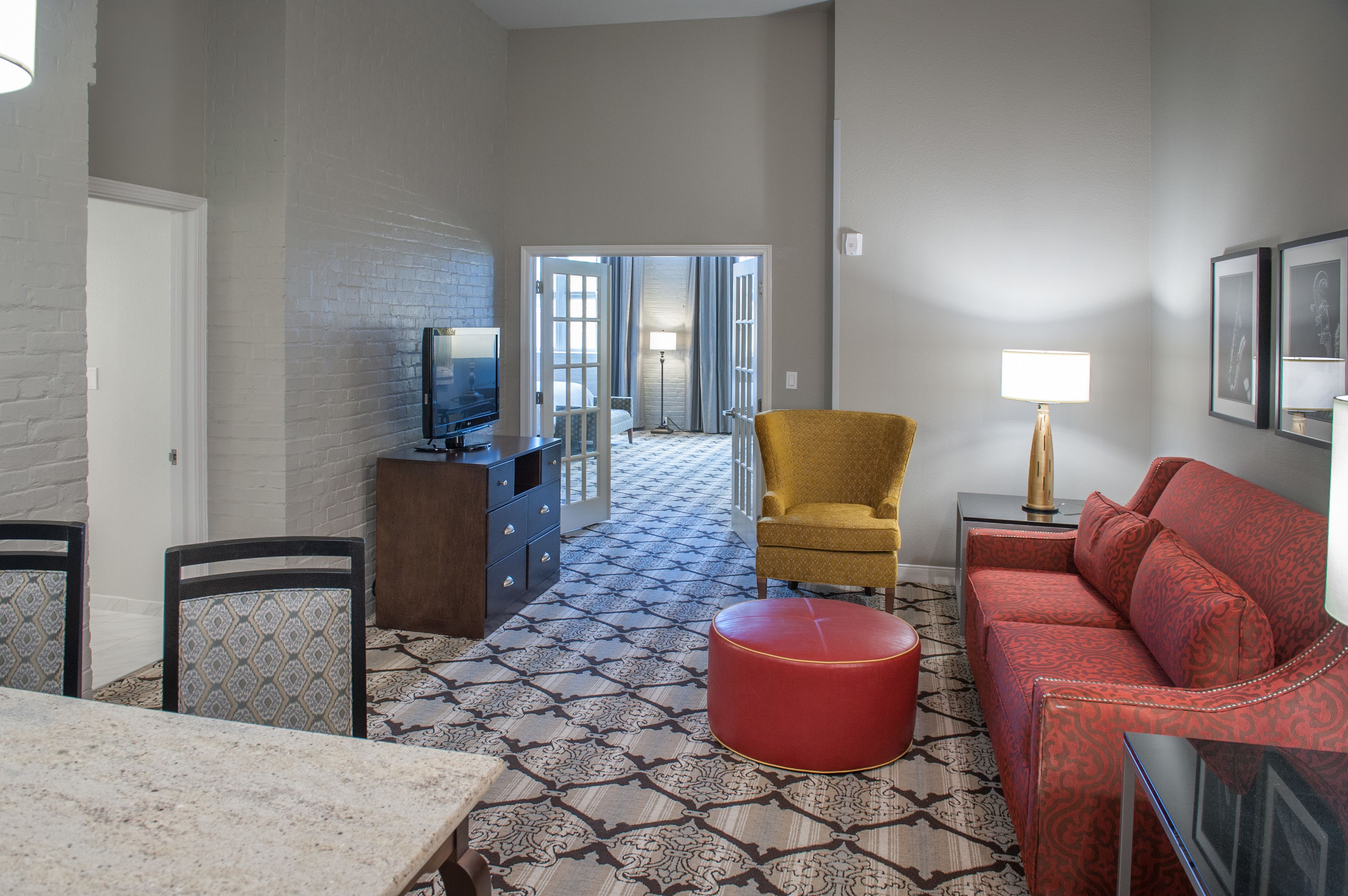 A living room with a patterned floor, a sofa, a chair, a table, and a television.
