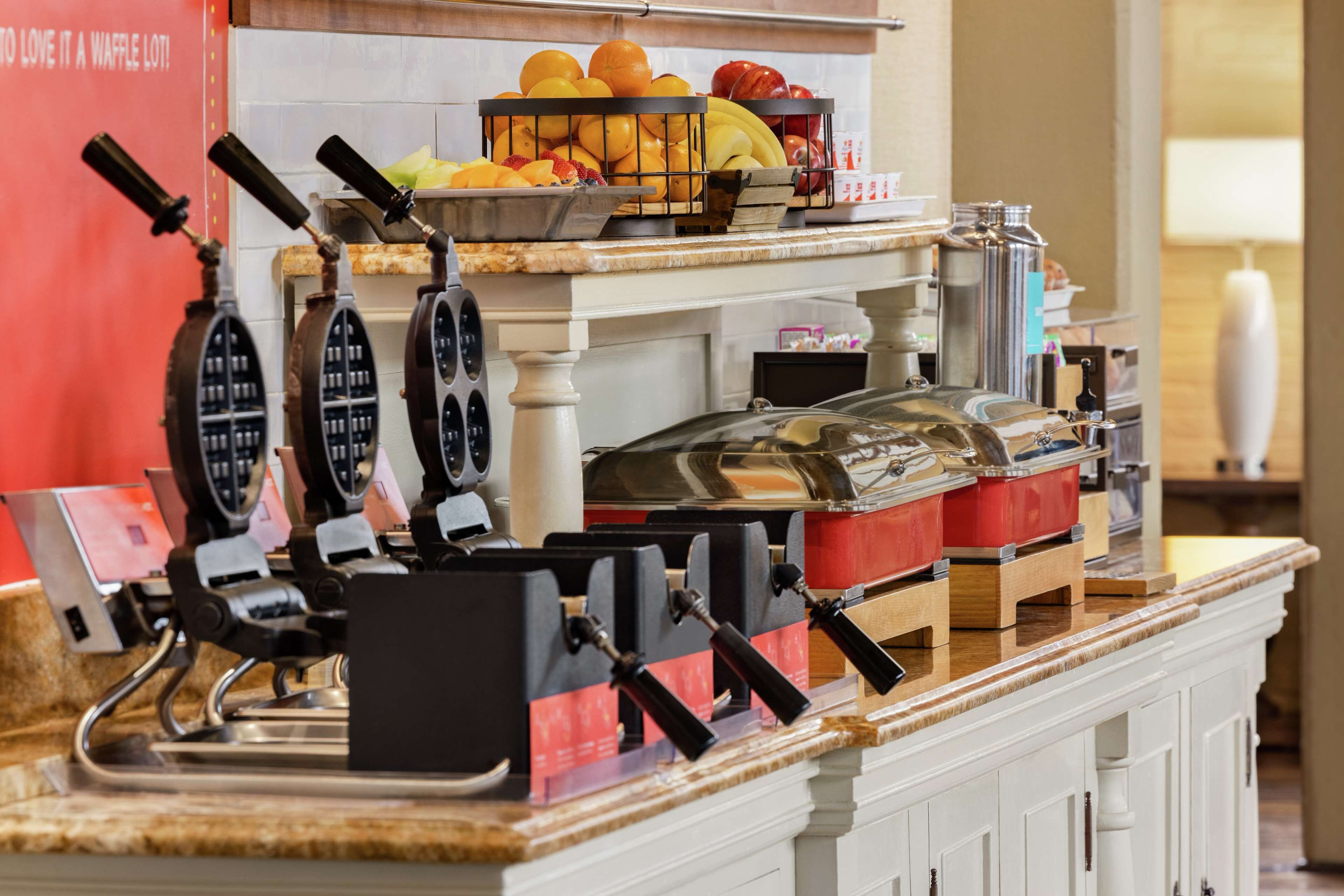 A buffet setup with waffle irons, fruit, and condiments.