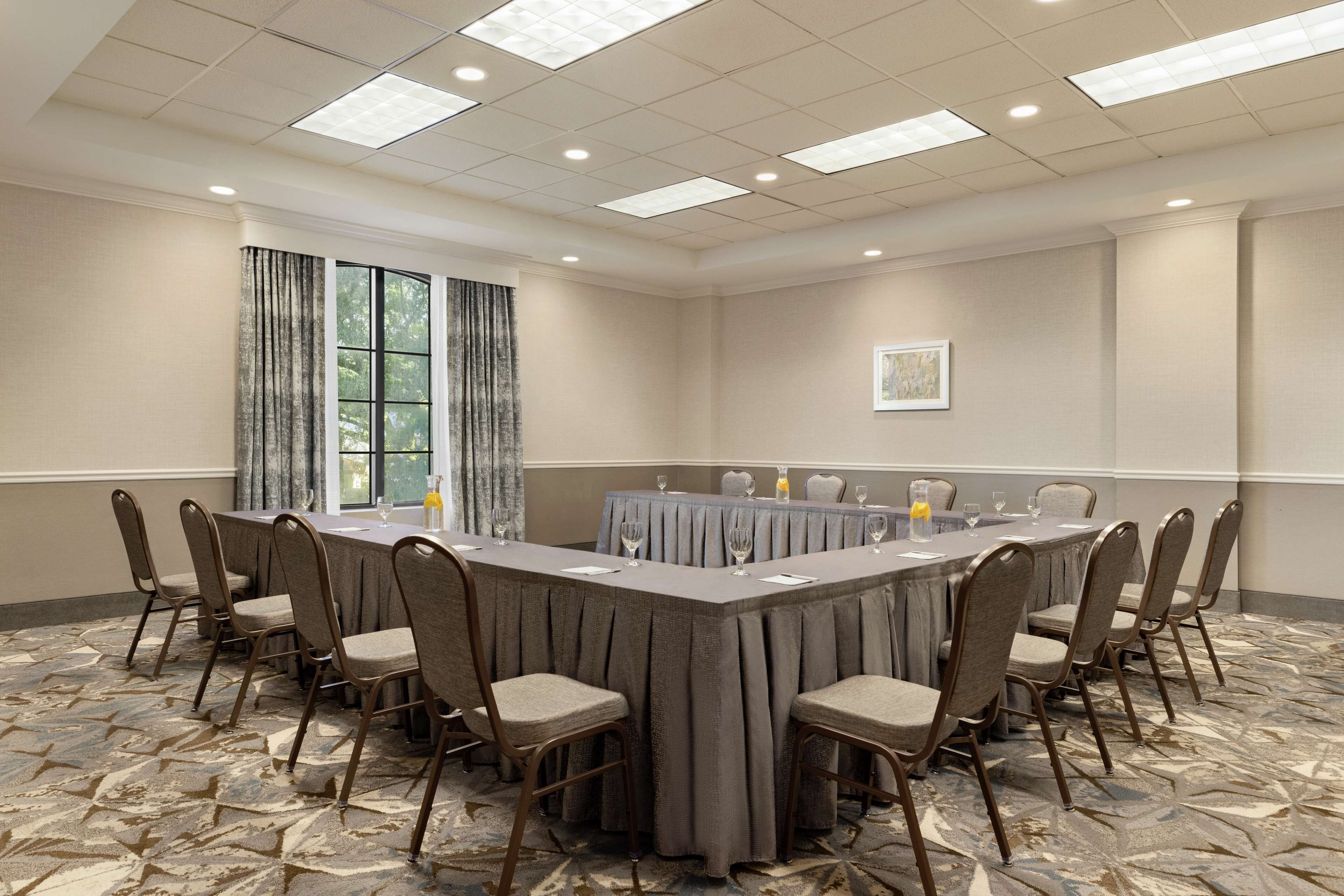 Une salle de conférence avec une longue table, des chaises et un tapis à motifs.