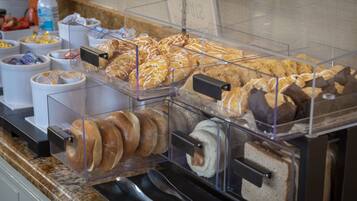 Un bufé de desayuno con diversos pasteles, sándwiches y bebidas.
