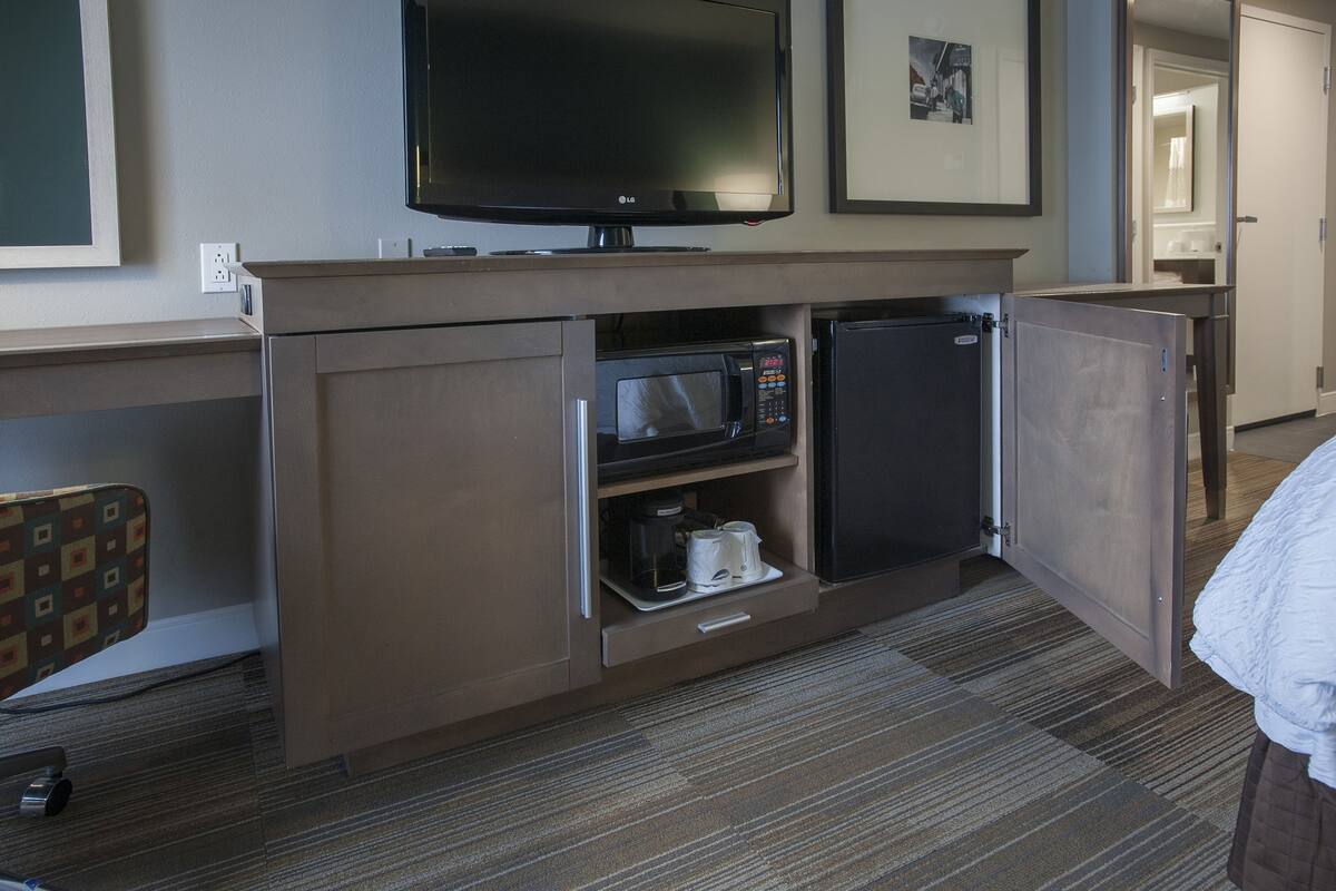A hotel room with a flat-screen TV, a microwave, and a mini-fridge.