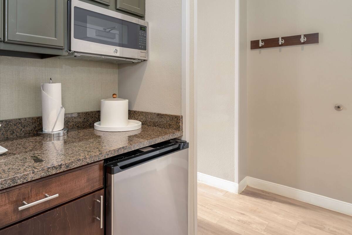 A kitchen with granite countertops, a built-in microwave, a paper towel dispenser, and a dishwasher.