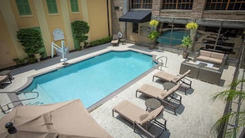 An outdoor swimming pool with lounge chairs and a covered seating area.