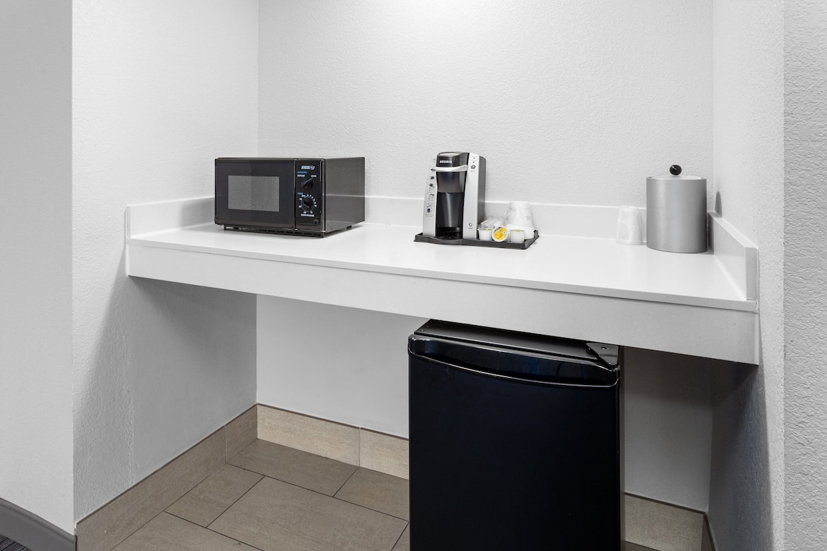 A kitchenette with a microwave, coffee maker, and a trash bin.