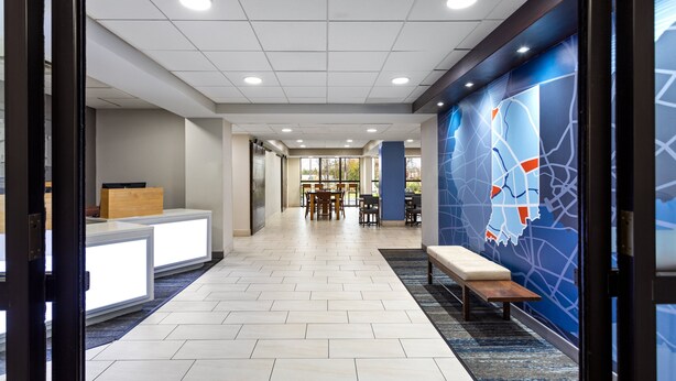 A hotel lobby with a reception desk, seating area, and a wall mural.