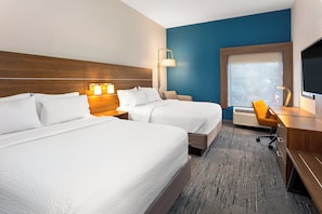 A hotel room with two beds, a desk, a chair, a television, and a window.