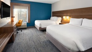 Habitación de hotel con dos camas, un escritorio, una silla, un televisor y una ventana con vistas a árboles.