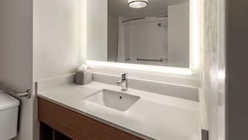 A bathroom with a white sink, a mirror, and a shower visible in the reflection.