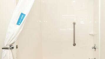 A shower with a grab bar, a white bathtub, and a white shower curtain with a label.