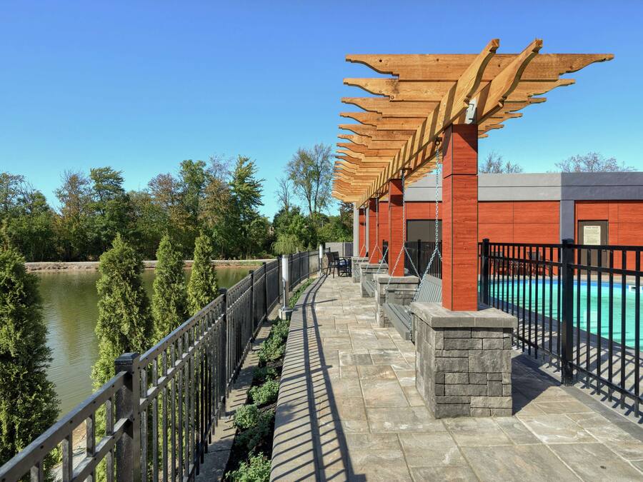 A bridge with a wooden pergola, a swimming pool, and a view of a river.
