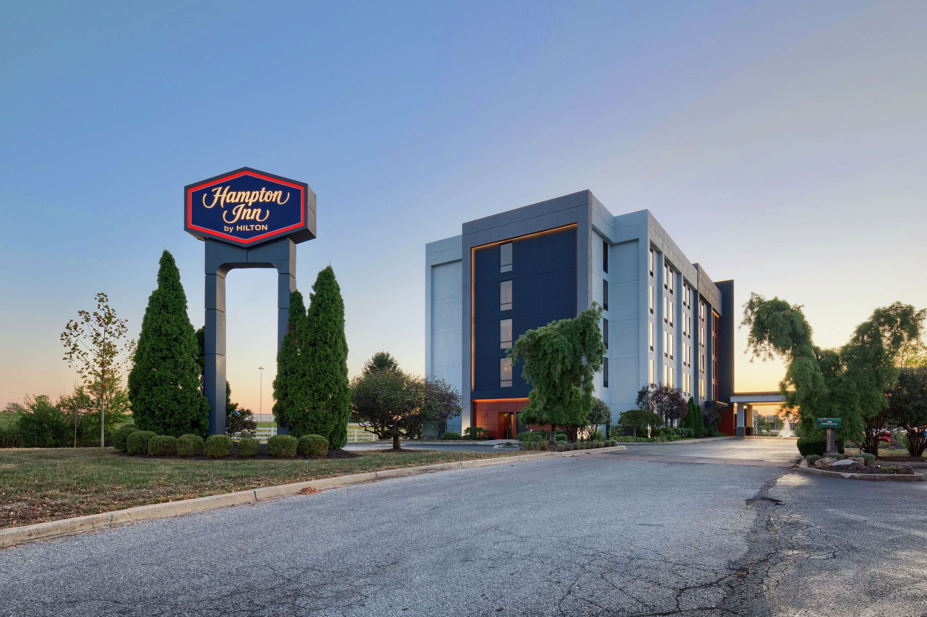Un hôtel Hampton Inn by Hilton au design moderne, doté d’une grande enseigne et d’un aménagement paysager bien entretenu.