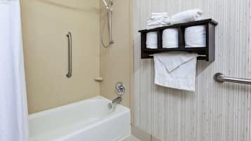 Un bagno con una vasca, una doccia e un portascopevoli con asciugamani piegati con cura.