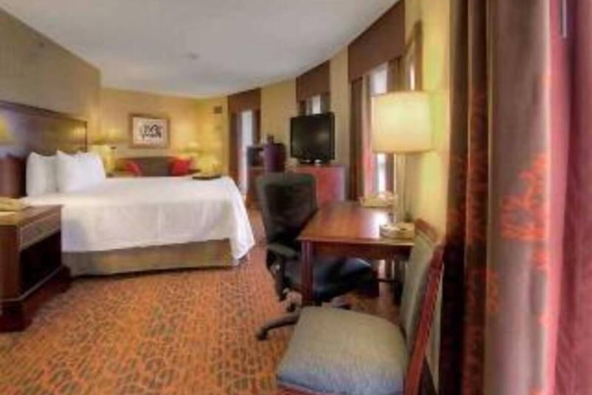 Una habitación de hotel con cama, escritorio, silla, televisor y ventana.
