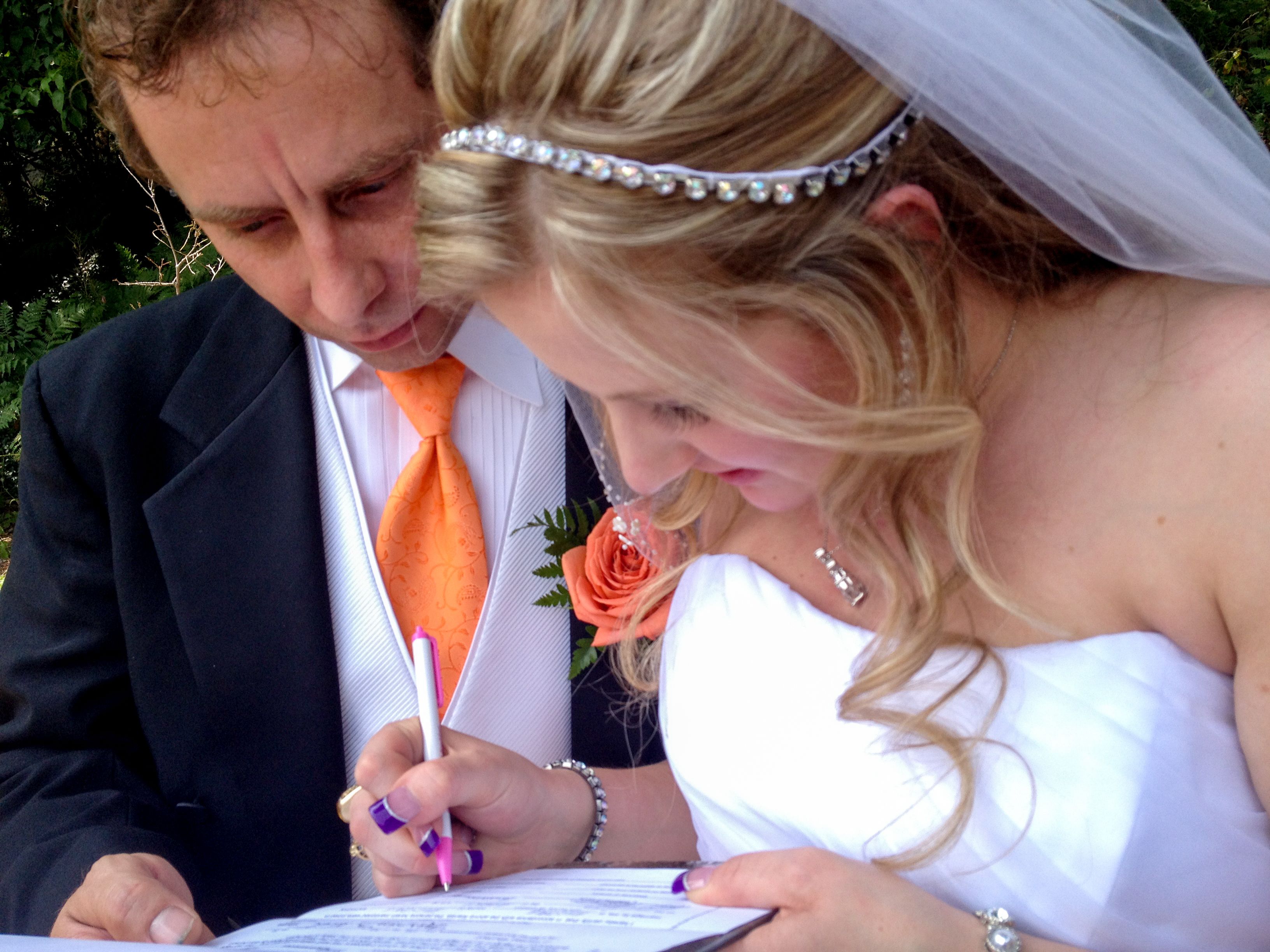 Una ceremonia de boda con una novia y un novio firmando un documento.