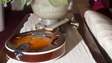 Una guitarra sobre una mesa, con una lámpara decorativa y un cojín al fondo.