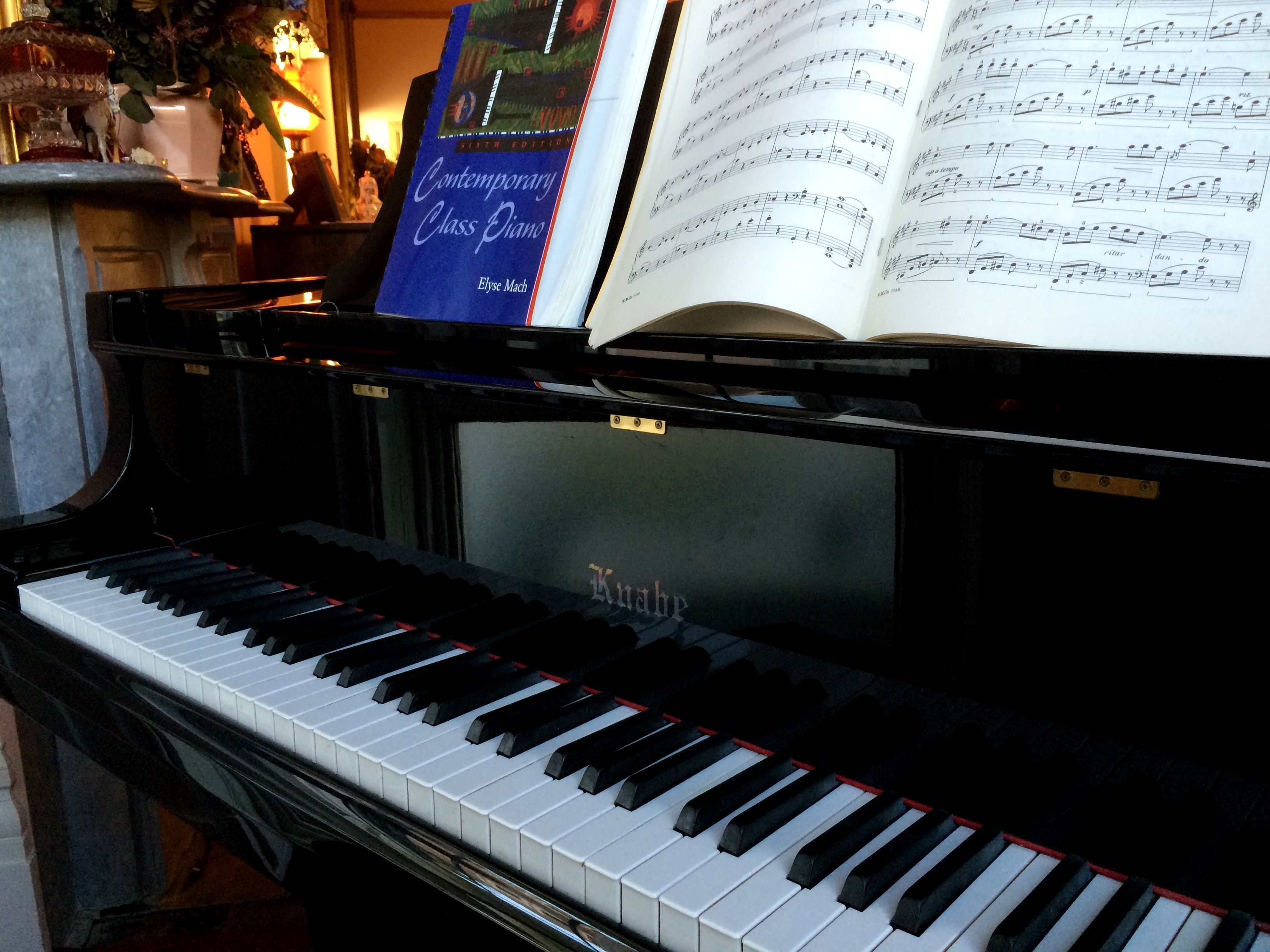 Un piano con partituras encima y un libro a su lado.