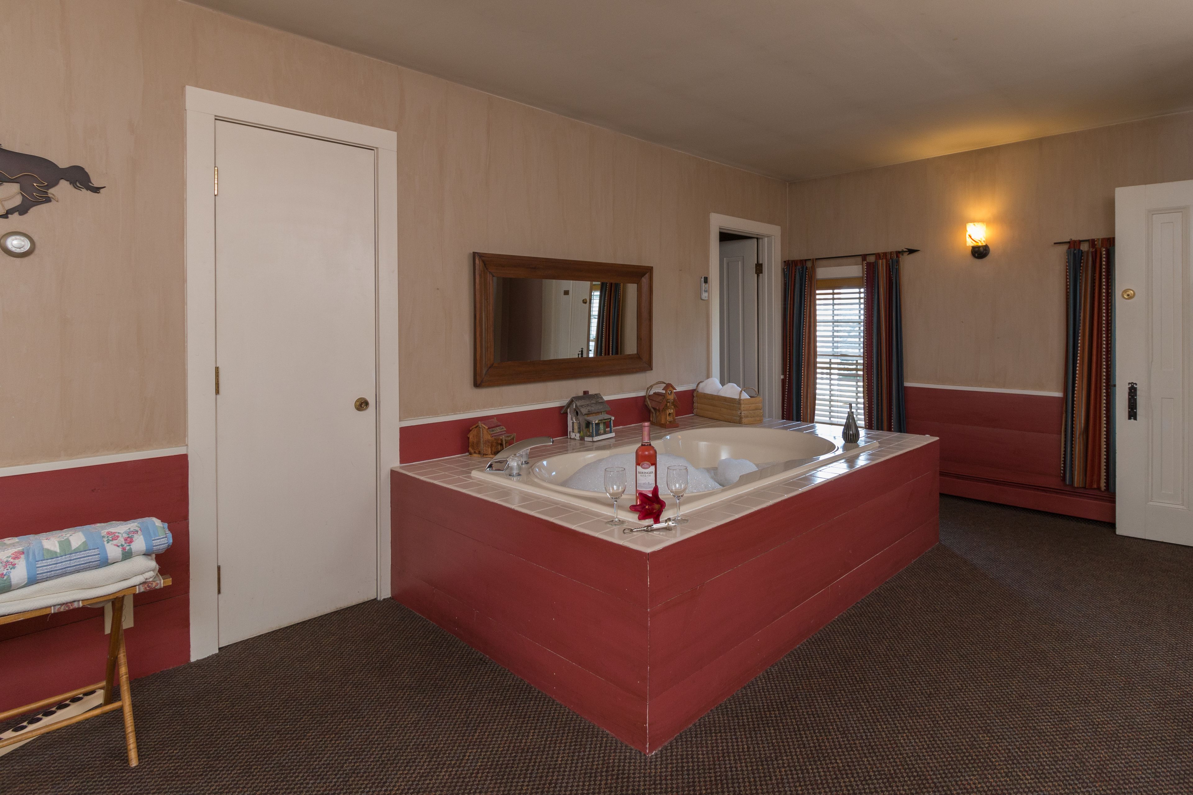 A bathroom with a large bathtub, a mirror, and a sink.