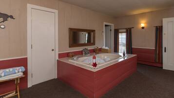 A bathroom with a large bathtub, a mirror, and a sink.