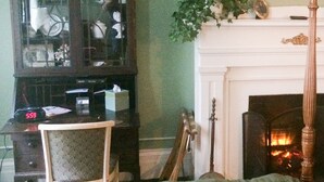 A room with a fireplace, a green armchair, and a wooden chair.