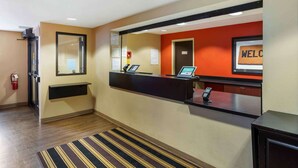 A hotel reception area with a reception desk, a fire extinguisher, a digital screen, and a welcome sign. - Extended Stay America Suites Meadowlands Rutherford (Rutherford)