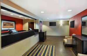A hotel reception area with a reception desk, a 'WELCOME' sign, a television, and seating. - Extended Stay America Suites Meadowlands Rutherford (Rutherford)