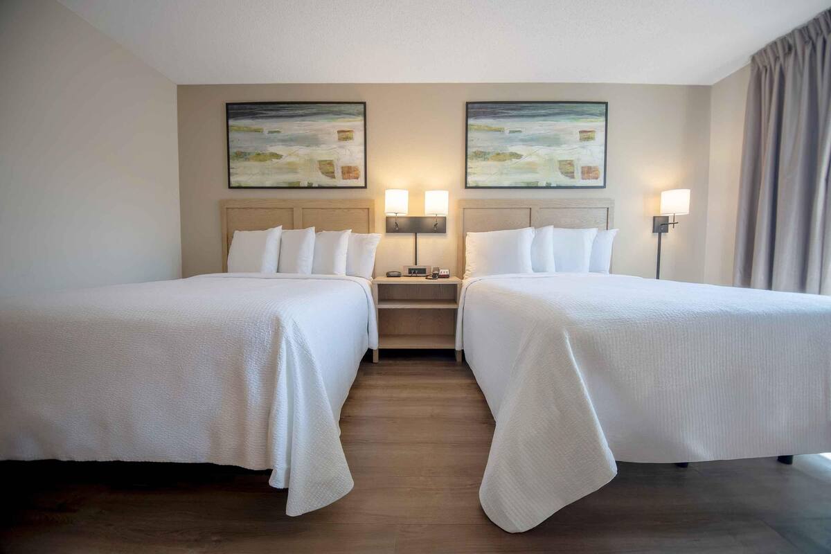 Een hotelkamer met twee bedden, een nachtkastje en twee wandlampen.