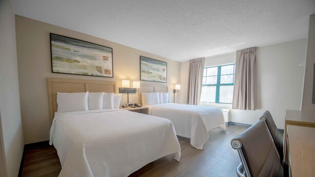A hotel room with two beds, a wooden floor, and a large window with curtains. - Extended Stay America Suites DC Fairfax Fair Oaks Mall (Fairfax)