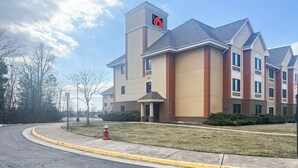 A multi-story hotel with a prominent '6' sign on the roof, a fire hydrant in front, and a well-maintained lawn.
