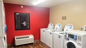 A laundry room with a red wall, a door with a keyhole, and multiple washing machines.