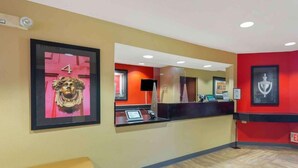 A reception area with a counter, a bench, and framed artwork on the walls. - Studio 6 – Chantilly, VA – Washington Dulles Airport (Chantilly)