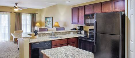 A compact kitchen with granite countertops, a refrigerator, and wooden cabinets.