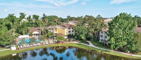 A resort with a swimming pool, guest lounge chairs, and a pond.
