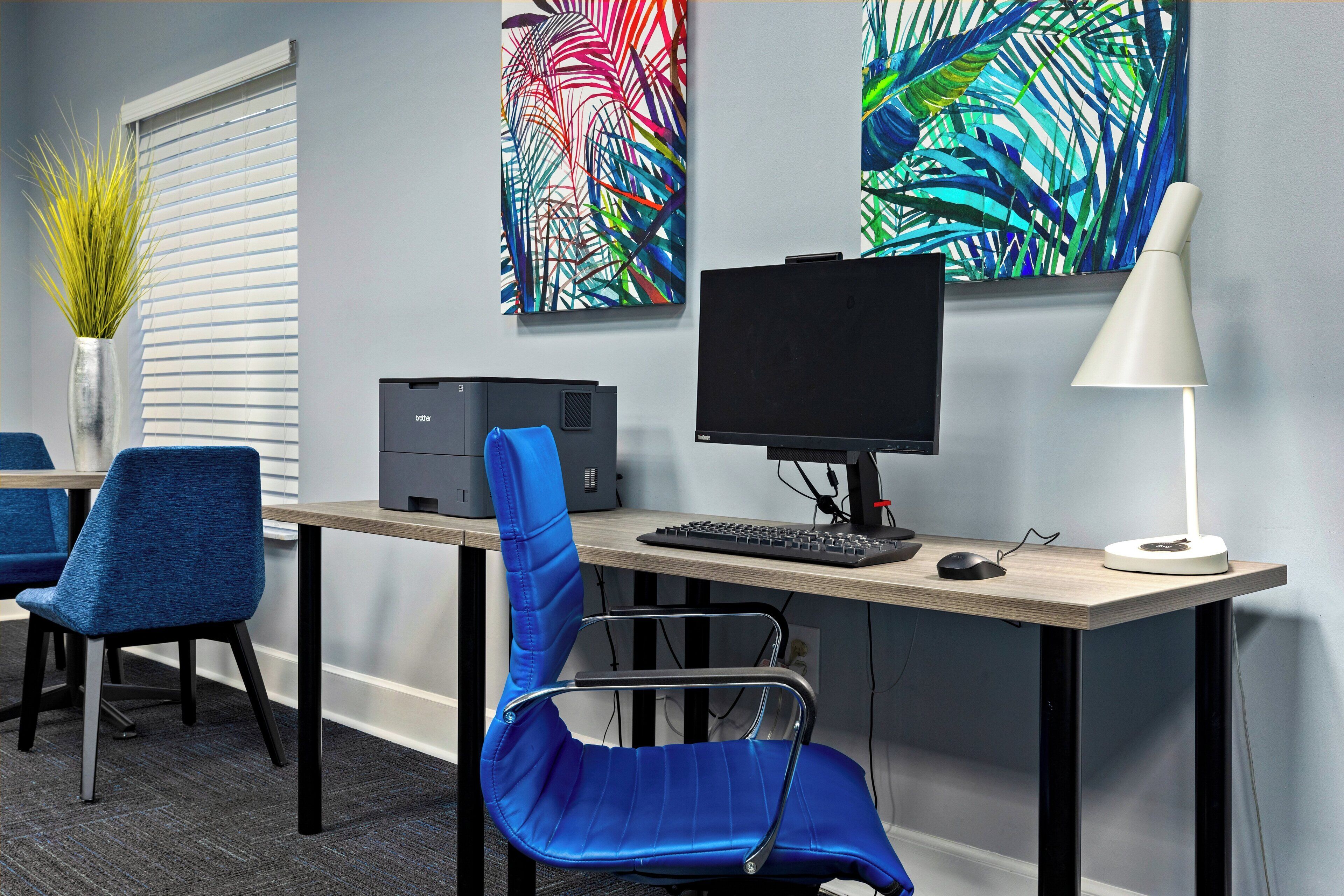 A modern office space with a desk, computer, and blue chairs.