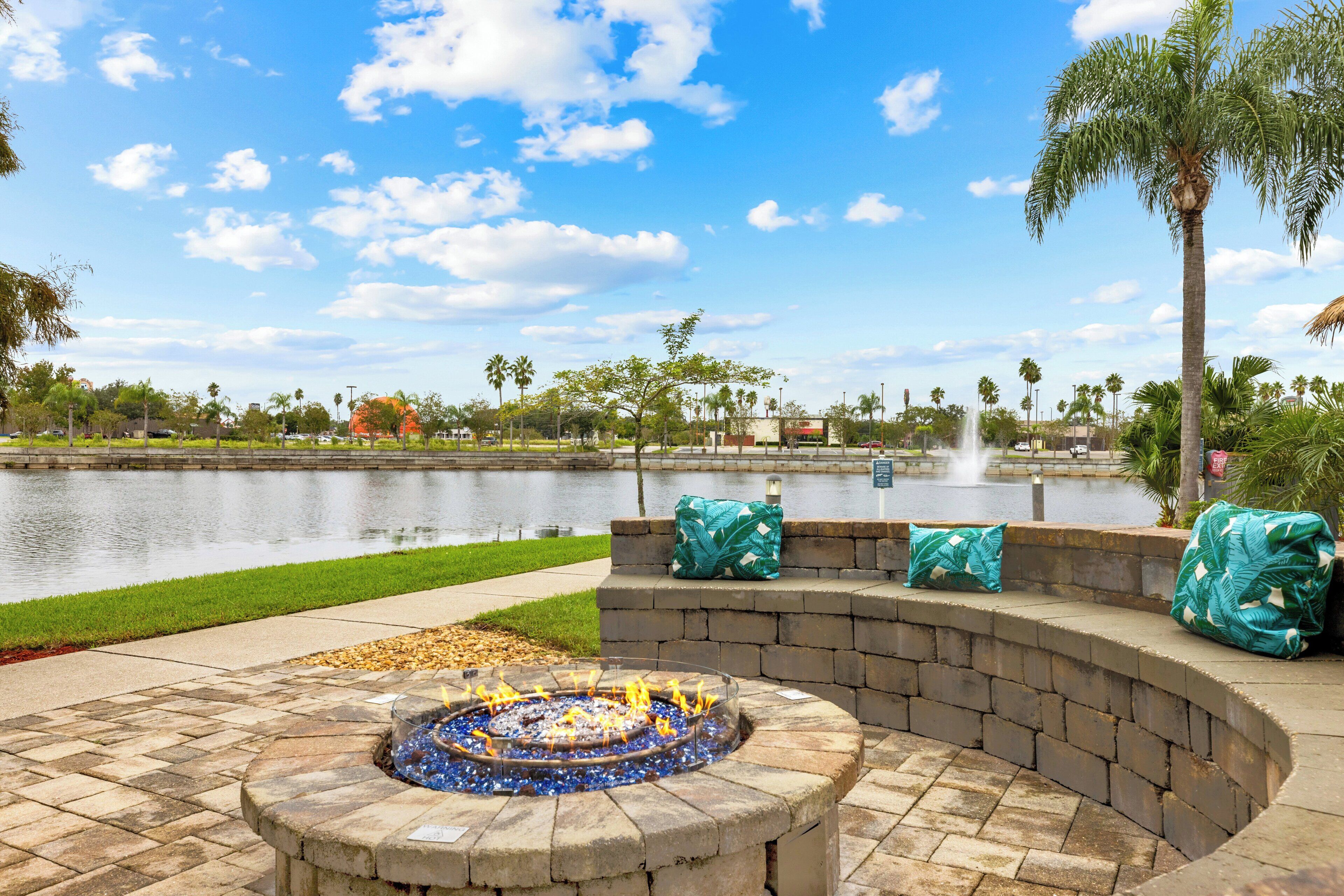 A fire pit with seating and a view of a lake.