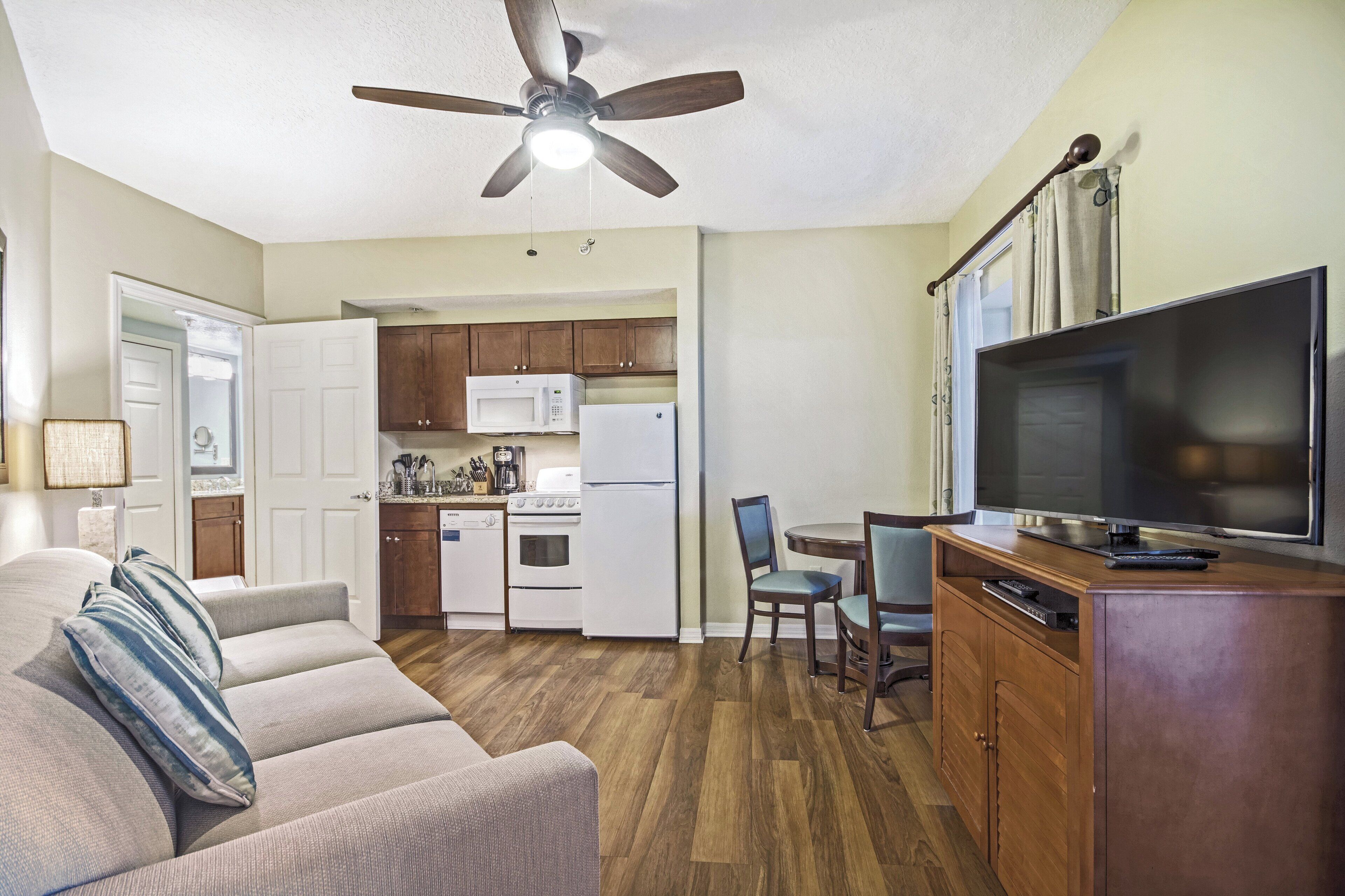 A compact living space with a kitchenette, a dining area, and a seating area with a sofa and chairs.