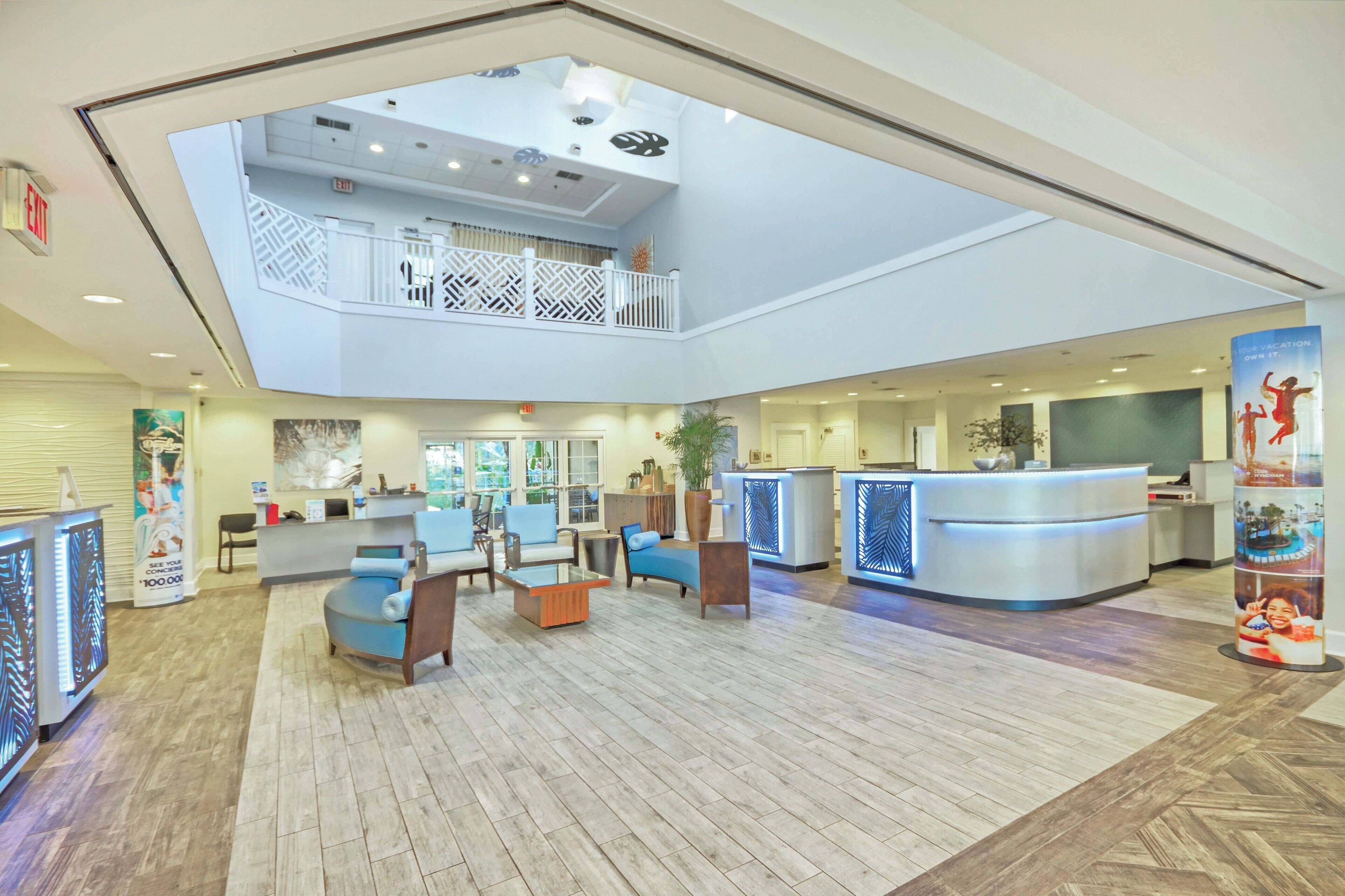 A spacious lobby with a reception desk, seating area, and a second-floor balcony.