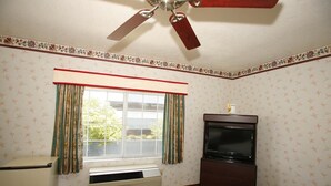 A room with a ceiling fan, a window with curtains, a television, and an air conditioning unit. - Hollywood Guest Inn (Los Angeles)