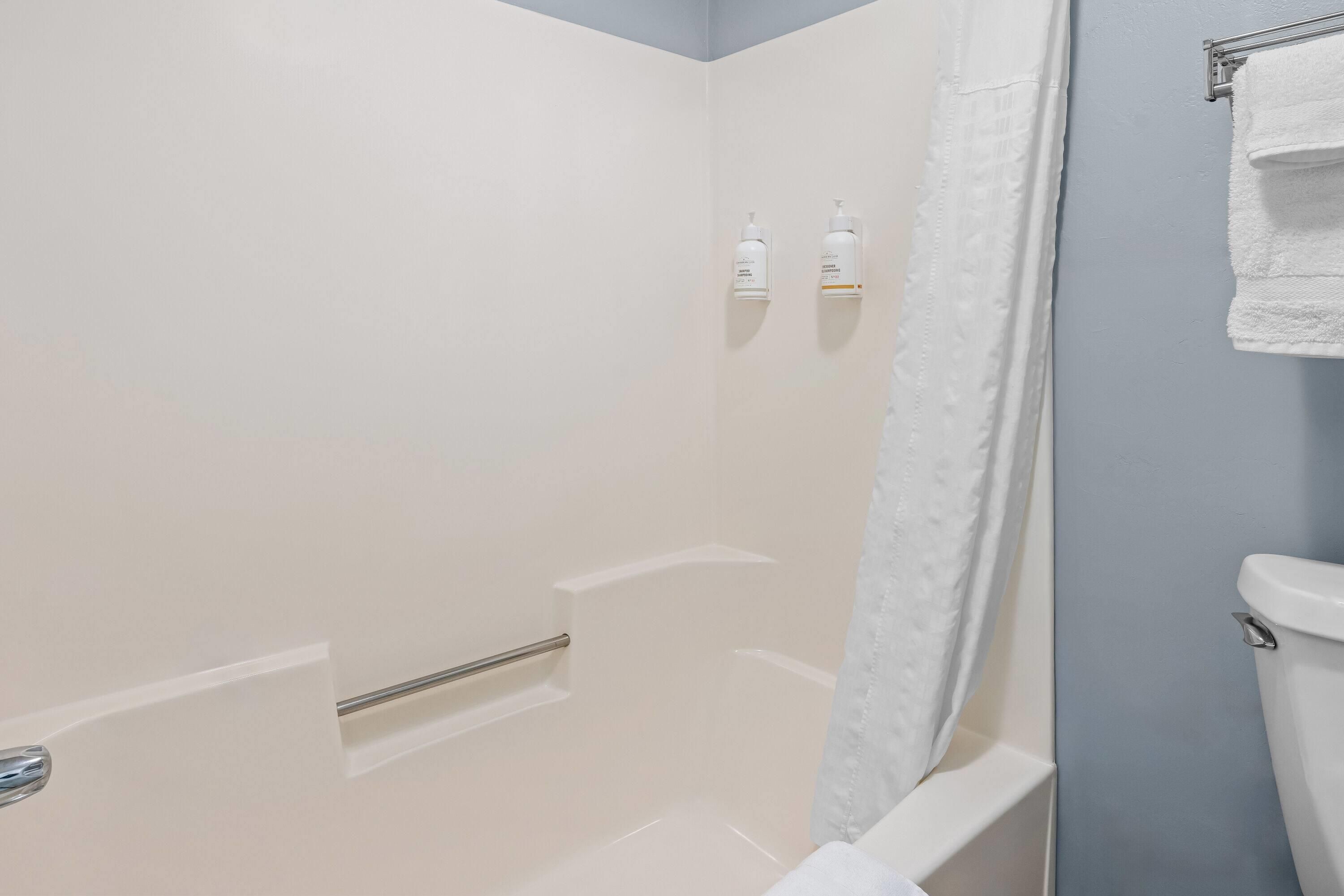 Une salle de bain avec douche, toilettes et porte-serviettes.